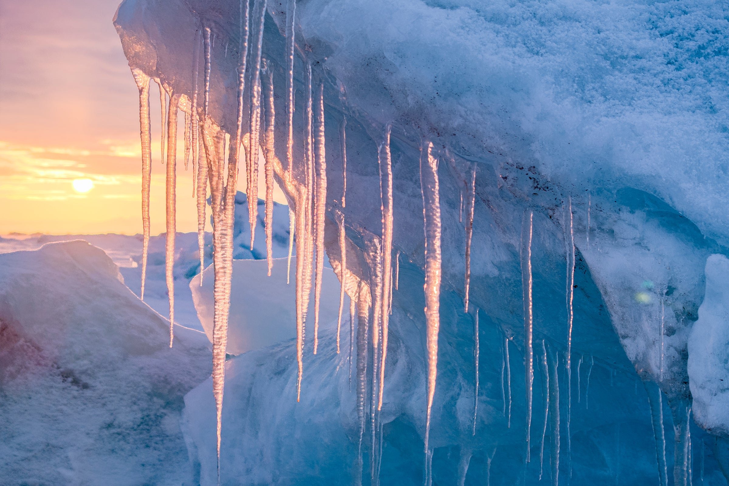 Icicles beneath an overhang of ice, warm light from a low sun
